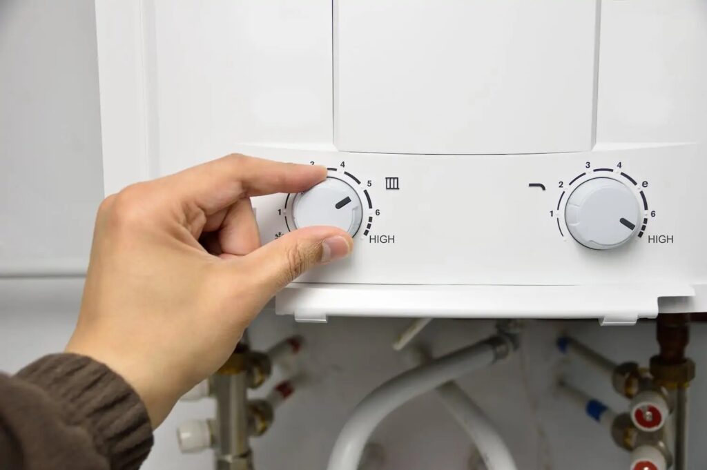 Close view of a woman's hand adjusting a knob on a tankless water heater.